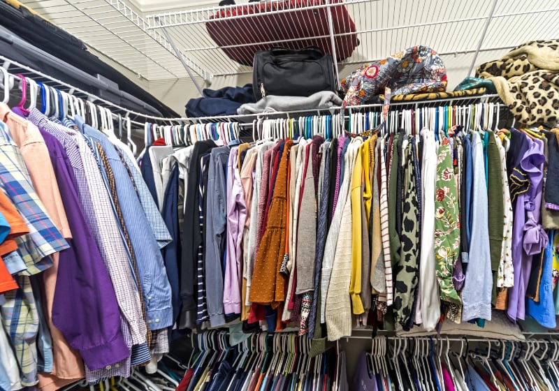 Unworn clothing piled in a wardrobe illustrating textile circularity barriers