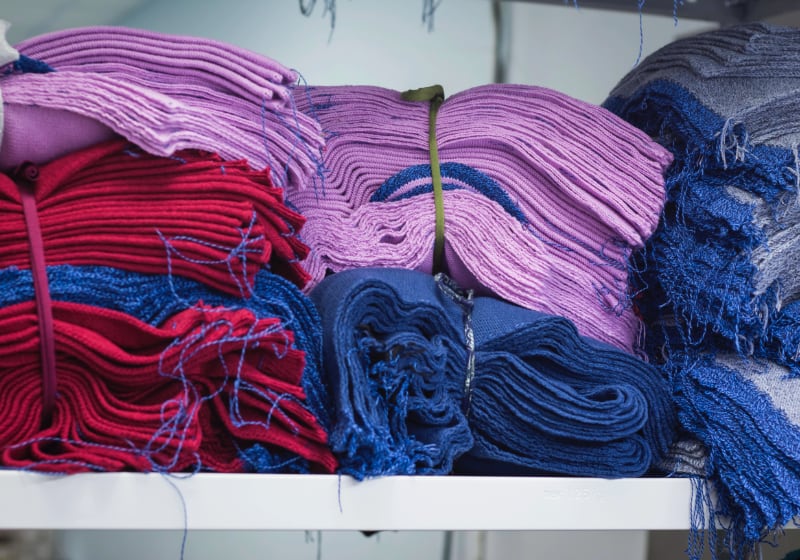 A pile of recently dyed red and blue fabrics folded on a shelf.