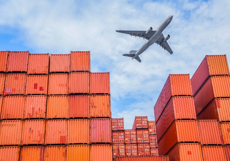 Plane flying over containers stacked on a dock