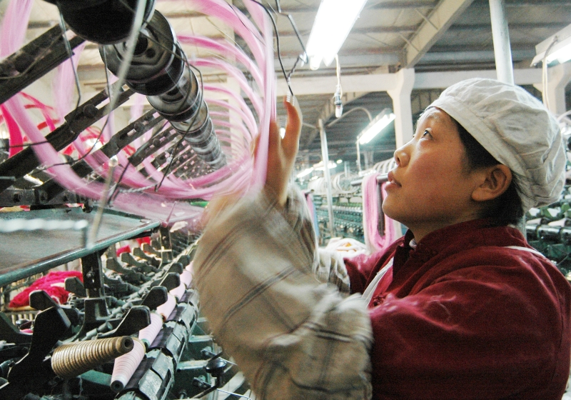 Woman in China operating spinning machine.