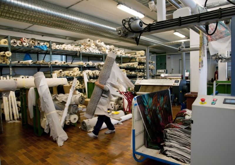 Textile worker carrying rolls of dyed fabrics
